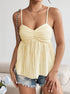 Woman wearing smocked yellow tank top with spaghetti straps and flared hem