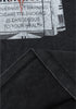 Zoom-in of hem stitching under warning label print on black tee.