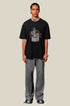 Male model wears black Yesskary tee with gray pants and chain necklace.
